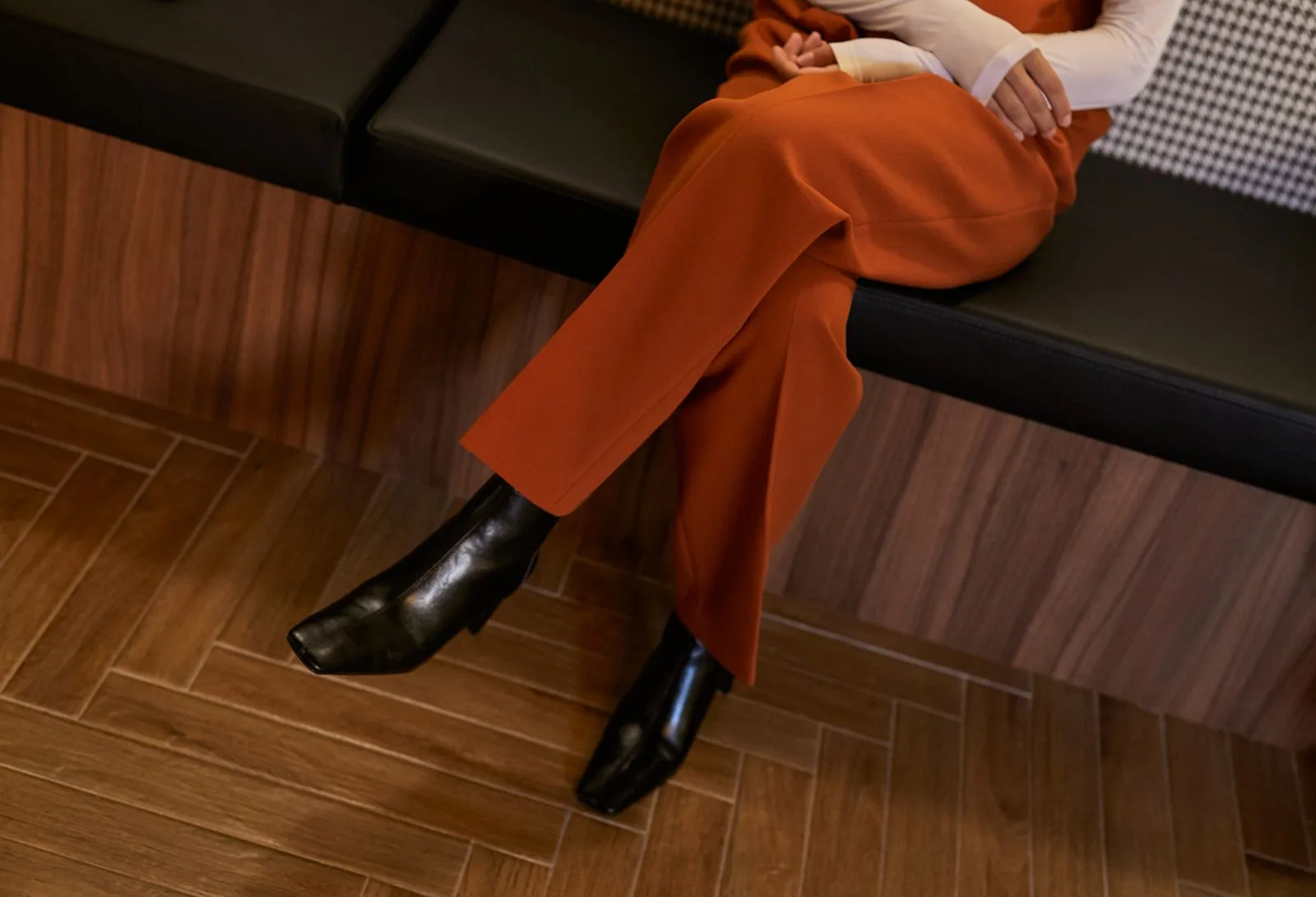 Bottes noires élégantes portées avec un pantalon coloré, vue en contre-plongée