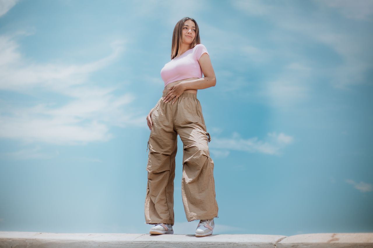 Femme portant un pantalon cargo beige ample avec poches latérales et un top rose